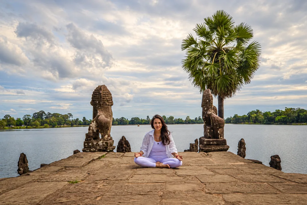 Marielisa Padilla in a lotus seat on the Srah Srang terrace, hands resting on her knees, palm and lake behind